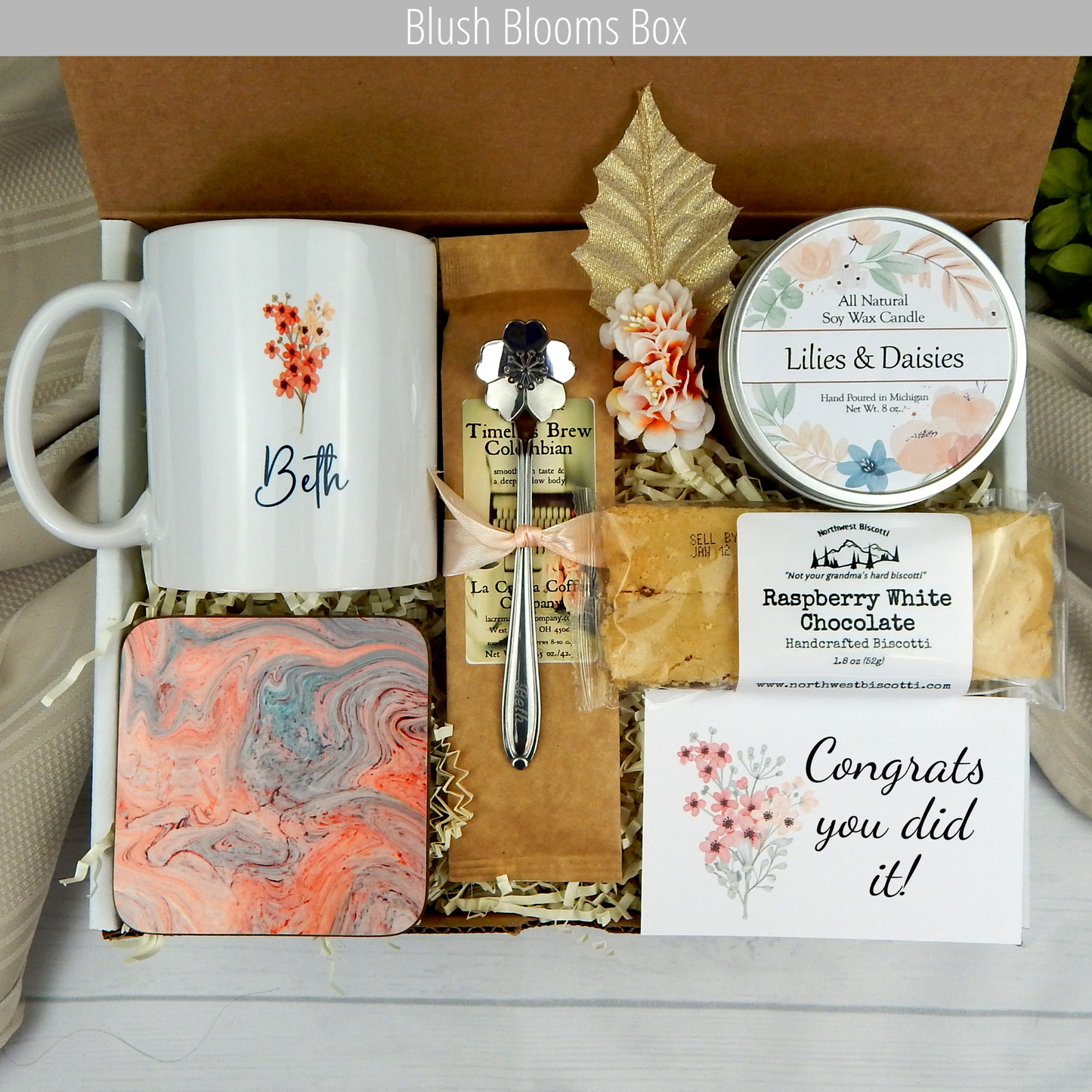 Celebrate success: Gift box with custom name mug, candle, engraved spoon, biscotti, and coffee for accomplishments.