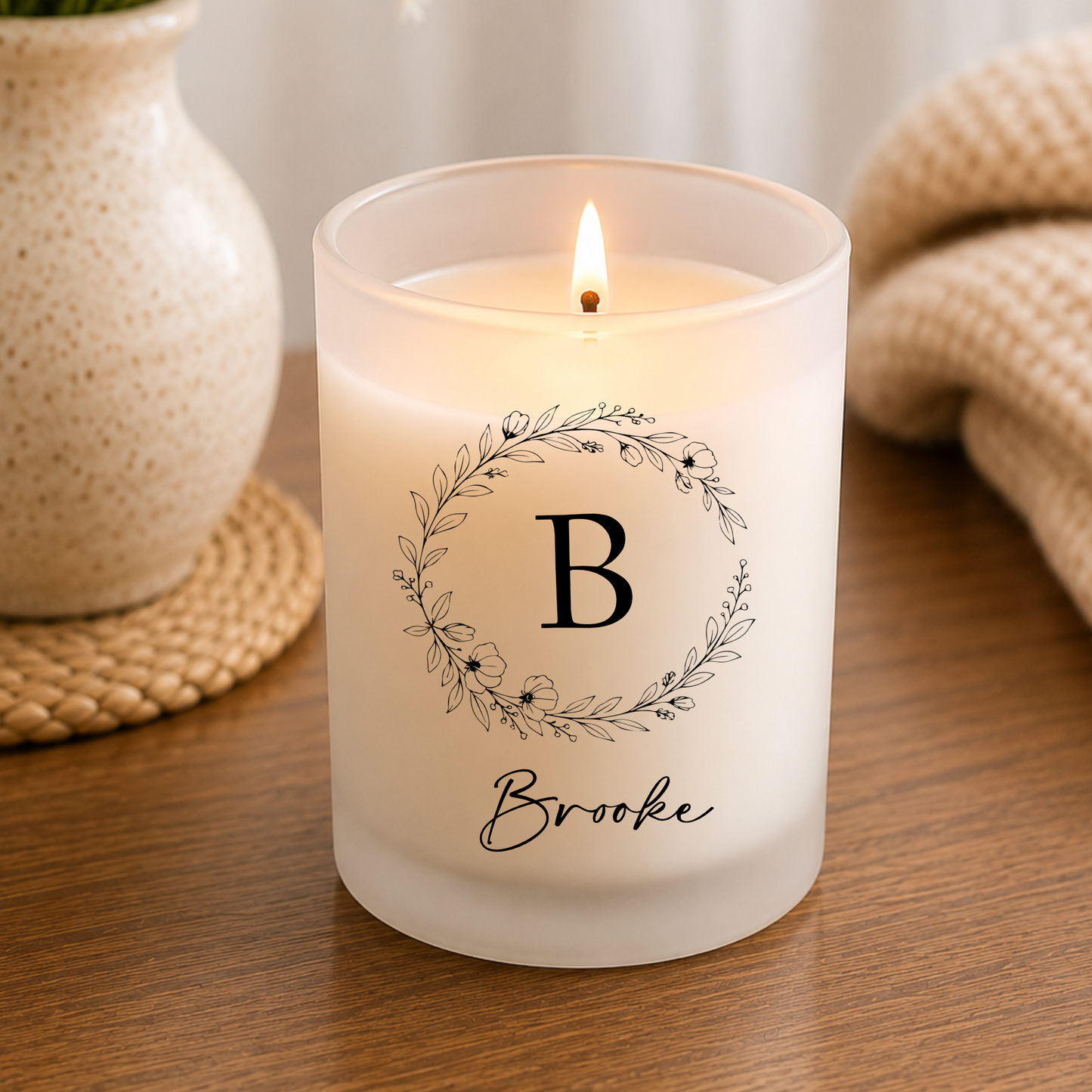 White candle shown personalized with graphic and name, lit on table setting
