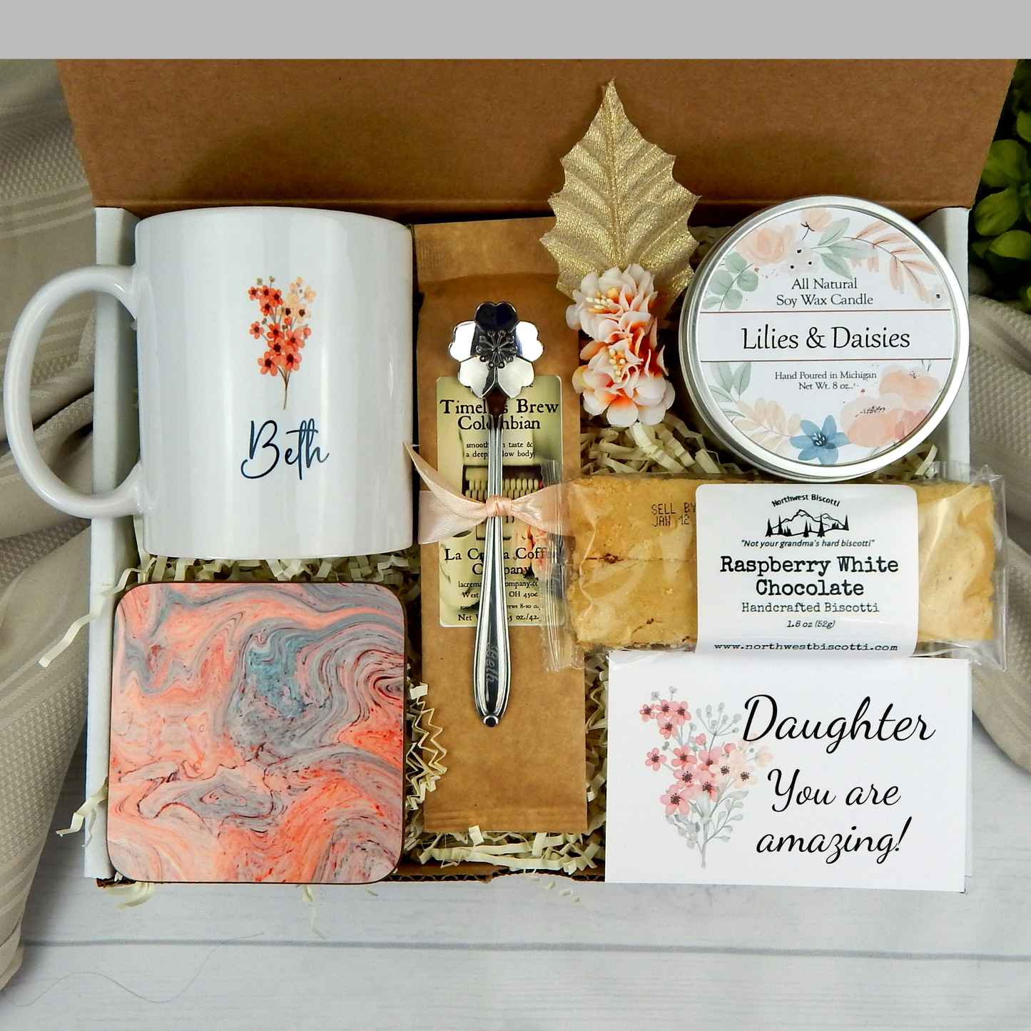 Thoughtful care package for your daughter: Personalized name mug, candle, engraved spoon, biscotti, and coffee.
