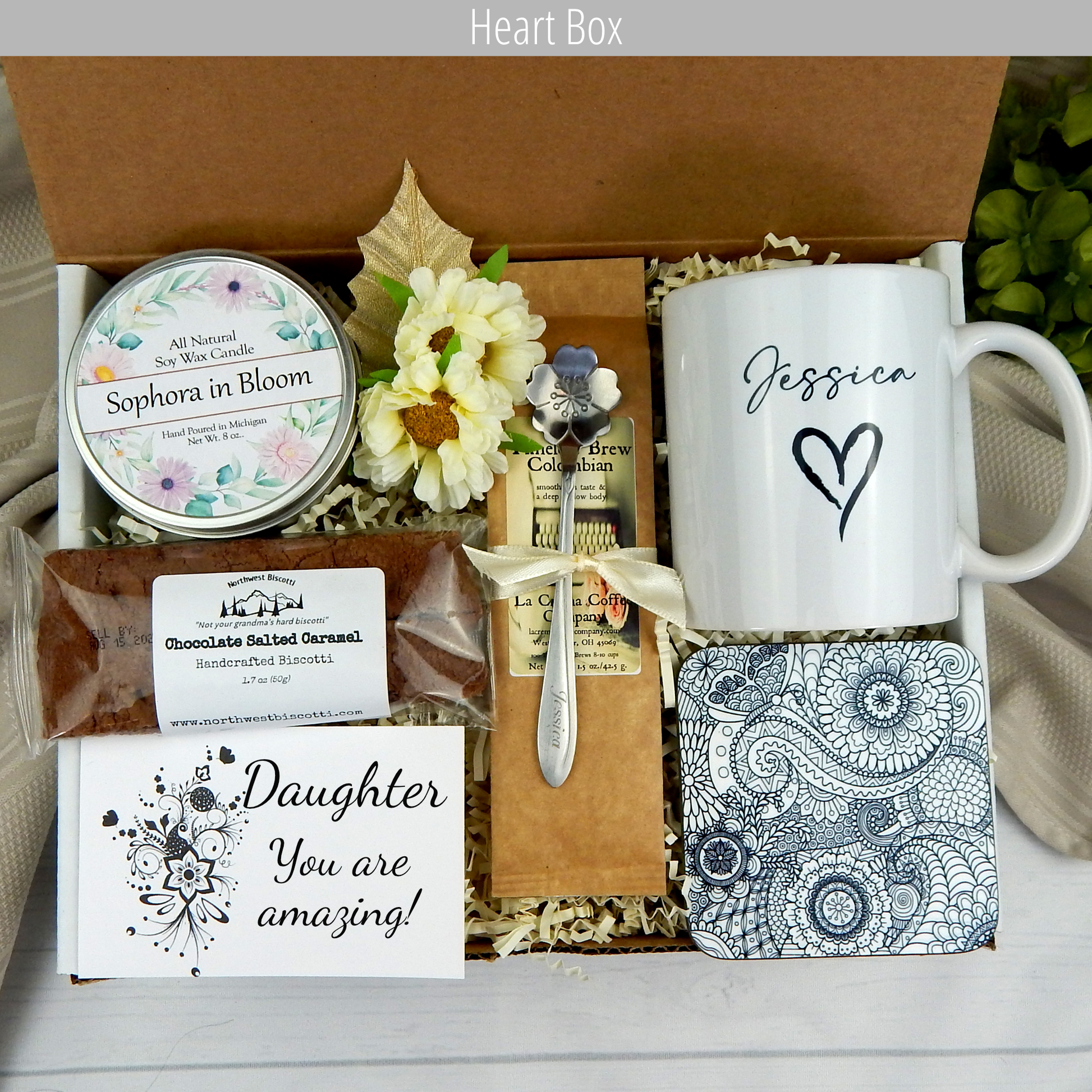 Daughter's joyous occasions: Women's gift basket featuring a personalized name mug, candle, engraved spoon, biscotti, and coffee.
