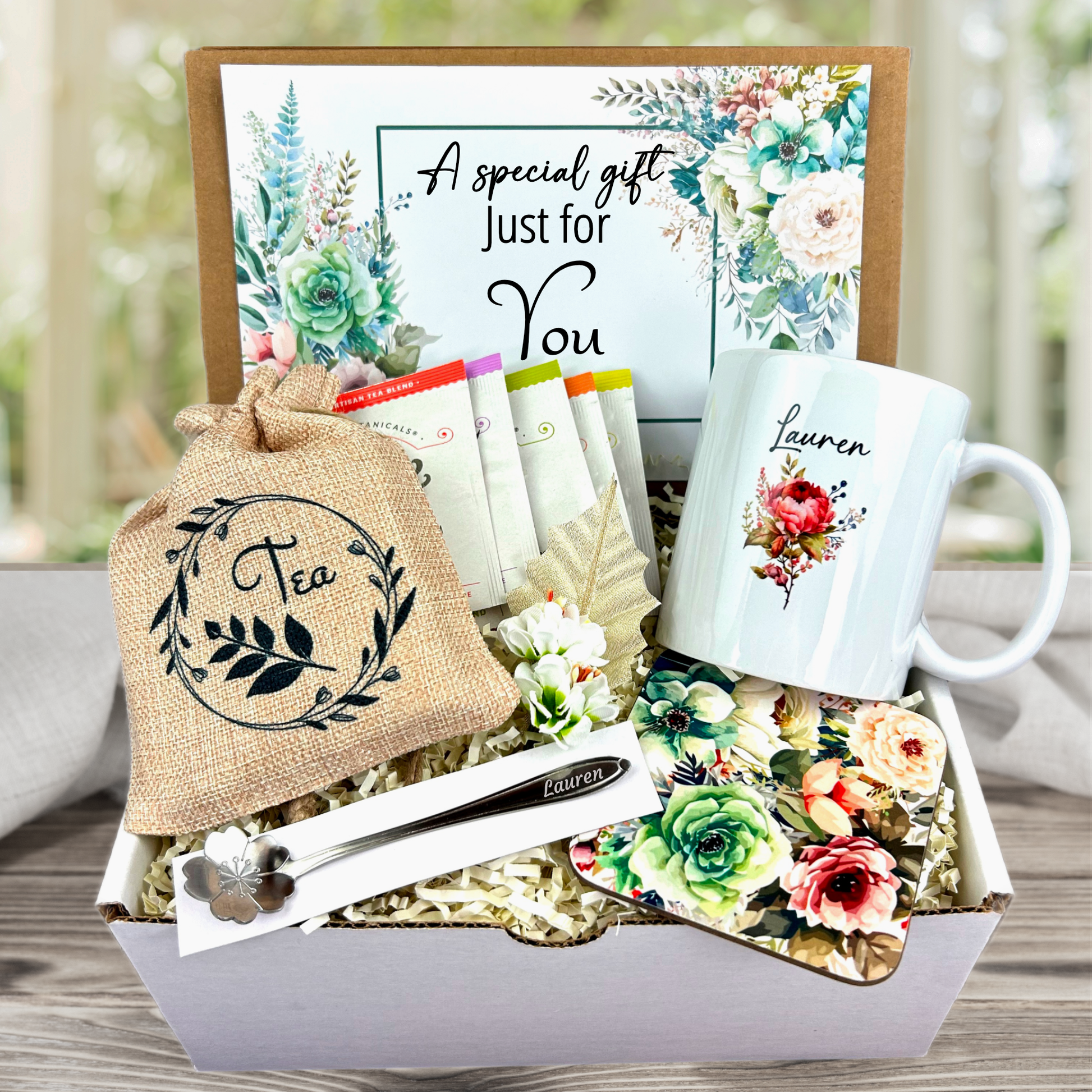 A special gift box with Personalized mug and engraved spoon set accompanied by a large 8-ounce scented candle, an assortment of five artisan teas, and a matching coaster set for a complete self-care experience
