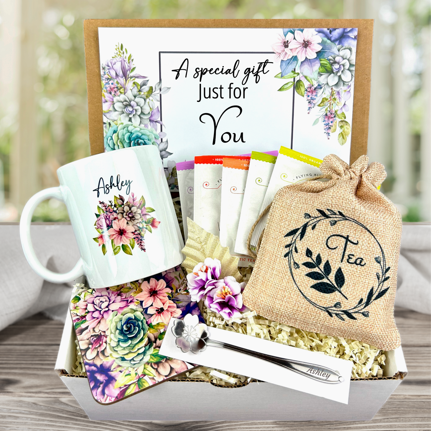 Personalized mug and engraved spoon set accompanied by a large 8-ounce scented candle, an assortment of five artisan teas, and a matching coaster set for a complete indulgent experience with Purple flower theme