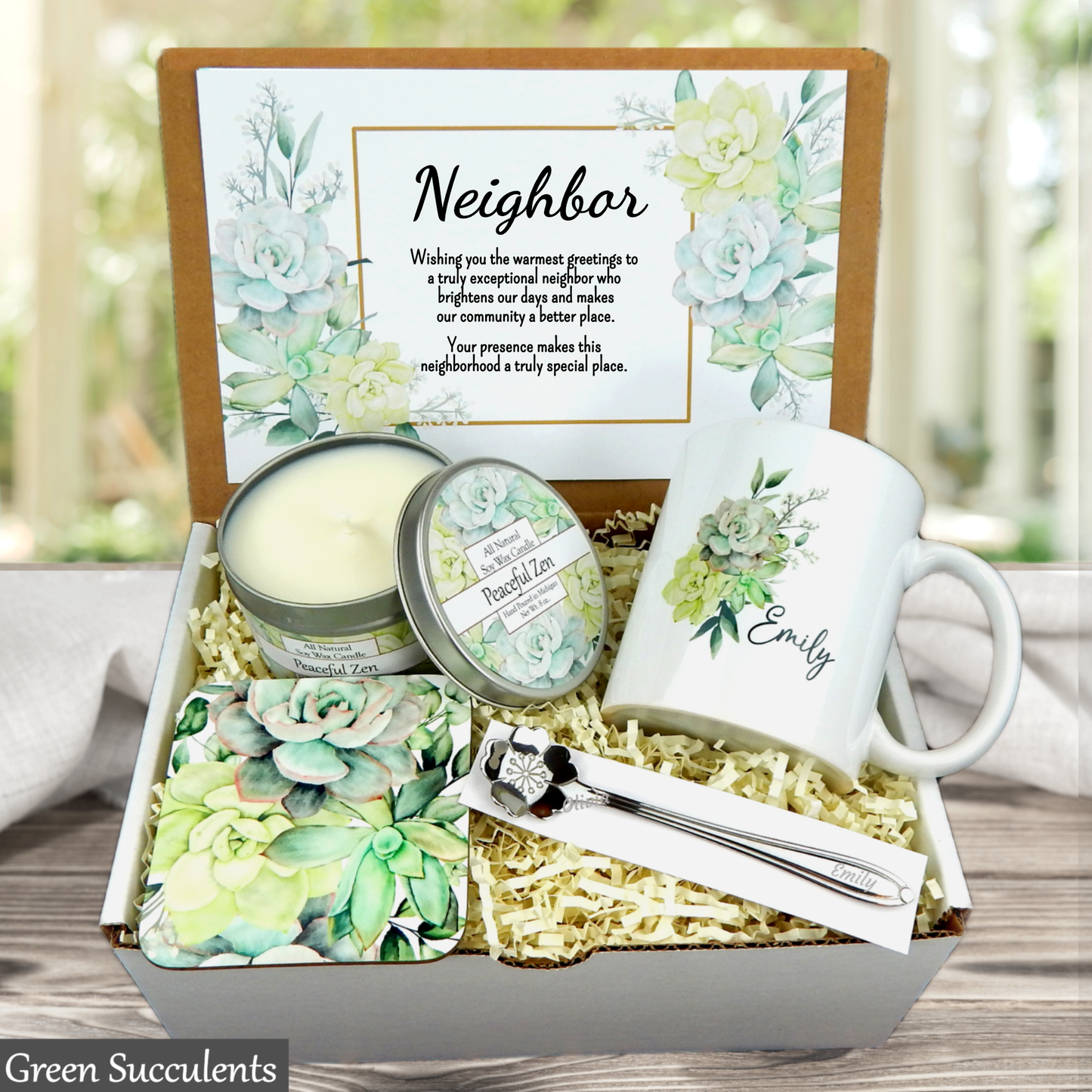 Gift box with a mug, candle, and tea set labeled 'Emily' on a wooden surface.